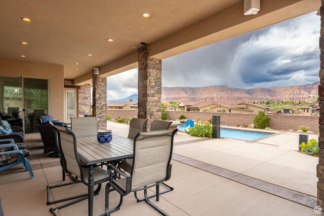 view of patio / terrace featuring outdoor dining area, fence, a mountain view, and a fenced in pool