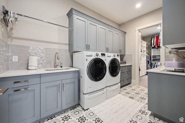 laundry room featuring washing machine and dryer, a sink, and cabinet space