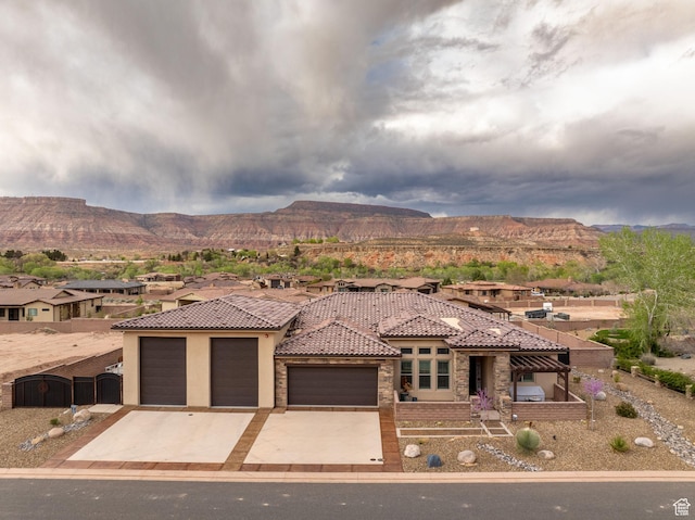 view of front of house featuring a tile roof, concrete driveway, stucco siding, an attached garage, and a mountain view