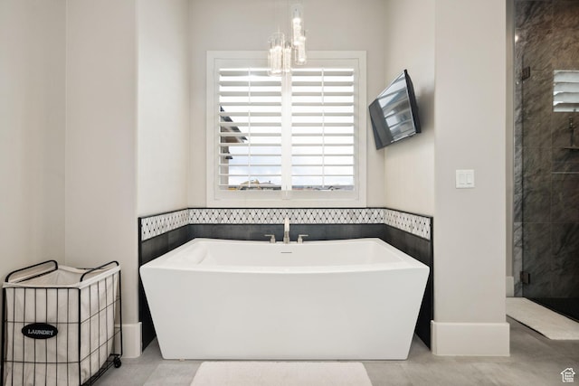 bathroom featuring a chandelier, a shower stall, and a freestanding bath