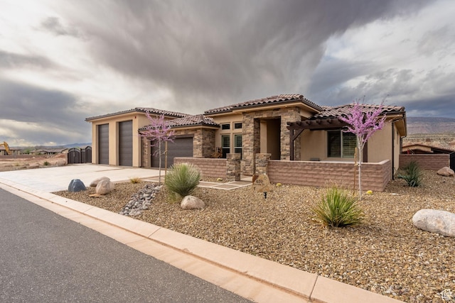 mediterranean / spanish-style home with a tile roof, driveway, stone siding, stucco siding, and a garage