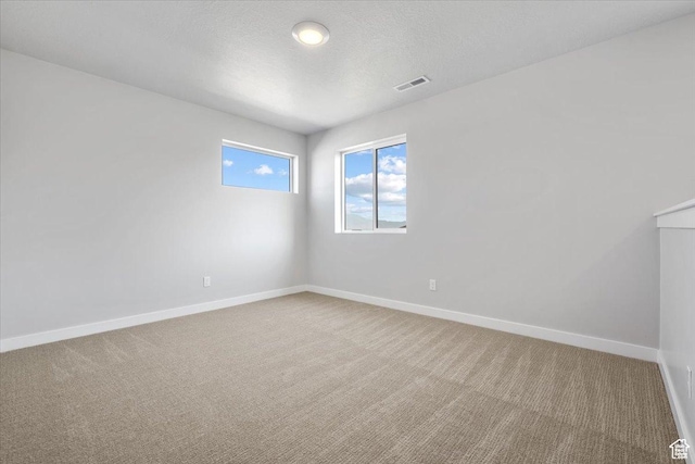 spare room with baseboards, visible vents, carpet flooring, and a textured ceiling