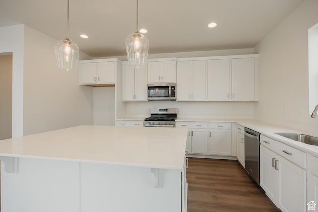 kitchen with a sink, appliances with stainless steel finishes, dark wood-type flooring, white cabinets, and recessed lighting