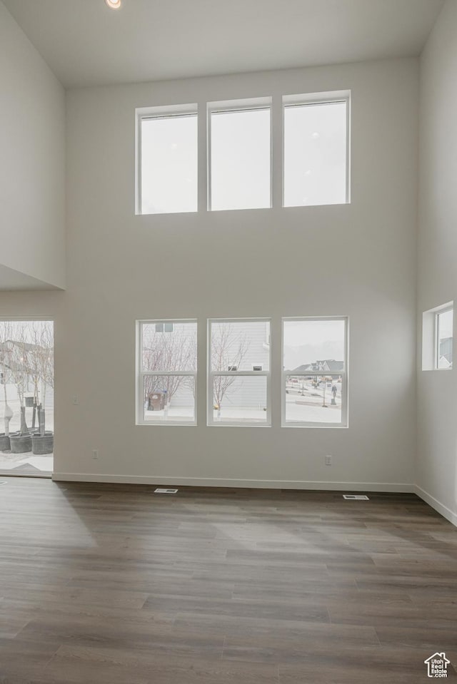 unfurnished room with a towering ceiling, baseboards, and wood finished floors