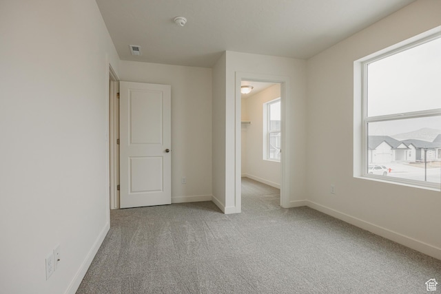 unfurnished bedroom with a walk in closet, baseboards, visible vents, and carpet flooring