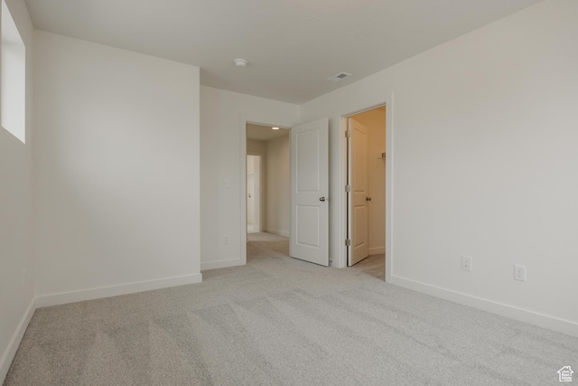 empty room featuring light colored carpet, visible vents, and baseboards