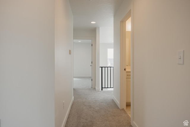 hall with baseboards, recessed lighting, and light carpet