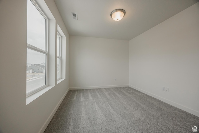 carpeted spare room featuring baseboards and visible vents