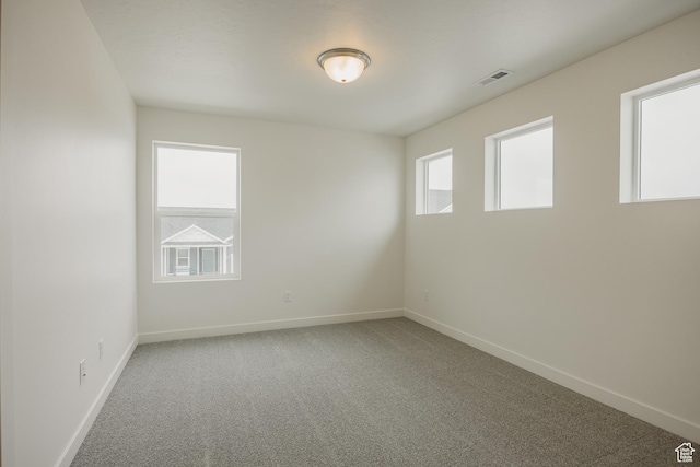 empty room with carpet floors, baseboards, and visible vents
