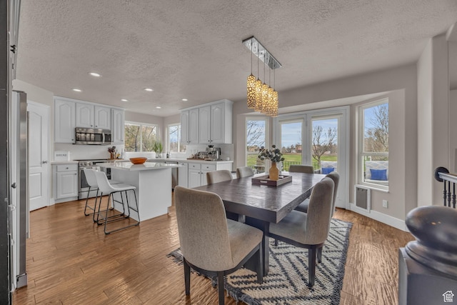 dining room with baseboards, wood finished floors, recessed lighting, and an inviting chandelier