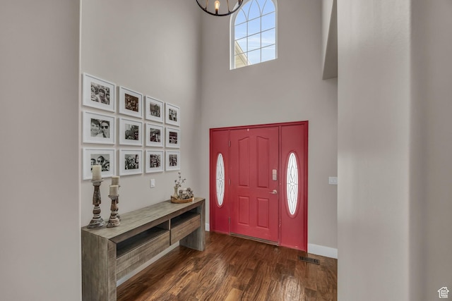 foyer entrance featuring baseboards, a high ceiling, an inviting chandelier, and dark wood-style flooring