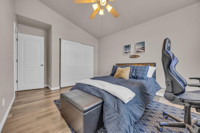 bedroom featuring lofted ceiling, baseboards, light wood finished floors, a ceiling fan, and a closet
