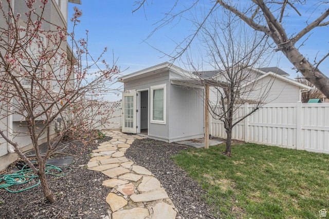 view of property exterior with a fenced backyard, an outdoor structure, and a yard