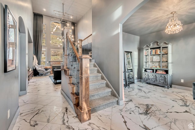 692 N Harrison Blvd, Ogden, UT 84404 - staircase with arched walkways, a chandelier, marble finish floors, baseboards, and a towering ceiling