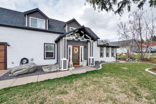 view of front of property with a shingled roof and a front yard