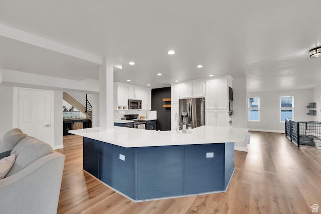 3225 N 1000 W, Pleasant View, UT 84414 - kitchen featuring light countertops, white cabinetry, appliances with stainless steel finishes, open floor plan, and light wood-type flooring