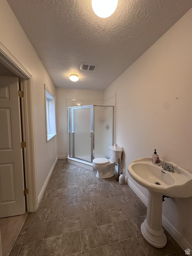 28848 N 11170 E, Milburn, UT 84629 - bathroom with toilet, a shower stall, a textured ceiling, baseboards, and visible vents