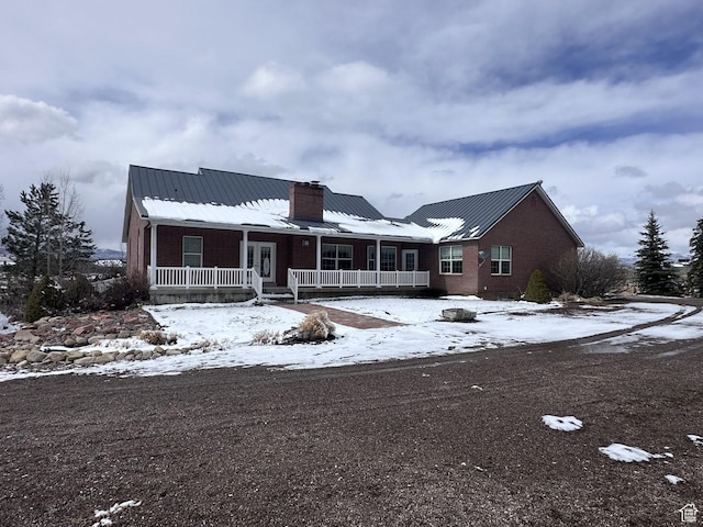 28848 N 11170 E, Milburn, UT 84629 - view of front facade featuring covered porch, a chimney, brick siding, and metal roof