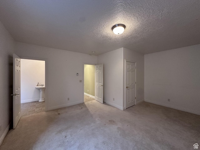 28848 N 11170 E, Milburn, UT 84629 - unfurnished bedroom featuring light colored carpet, ensuite bath, baseboards, and a textured ceiling