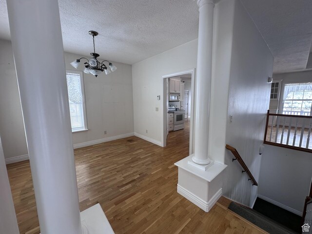 28848 N 11170 E, Milburn, UT 84629 - interior space featuring a textured ceiling, a notable chandelier, wood finished floors, and ornate columns