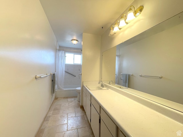 bathroom featuring toilet, stone tile floors, vanity, washtub / shower combination, and baseboards