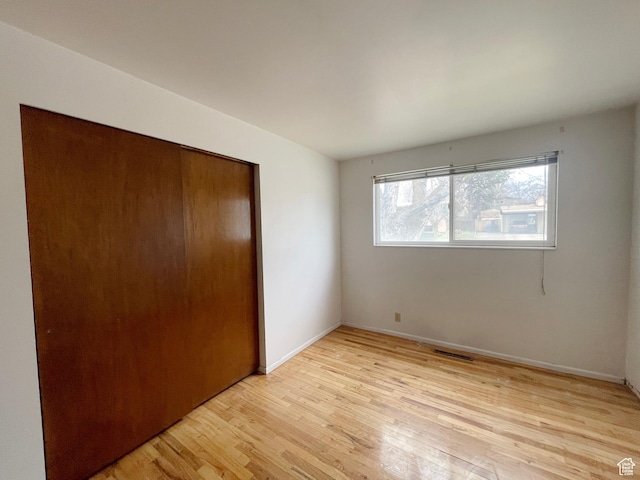 unfurnished bedroom with a closet, baseboards, and light wood-style floors