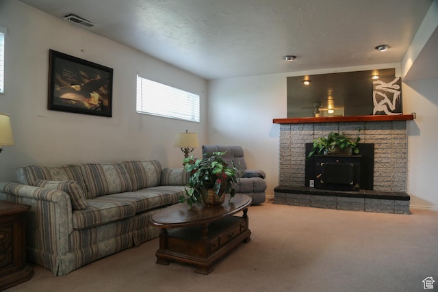carpeted living area with a brick fireplace, baseboards, and visible vents
