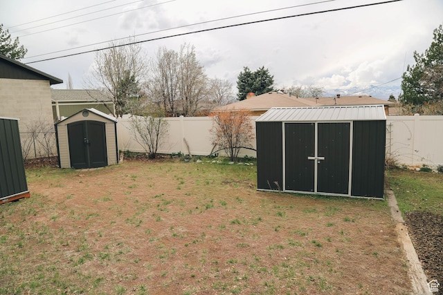 view of yard featuring an outbuilding, a fenced backyard, and a shed