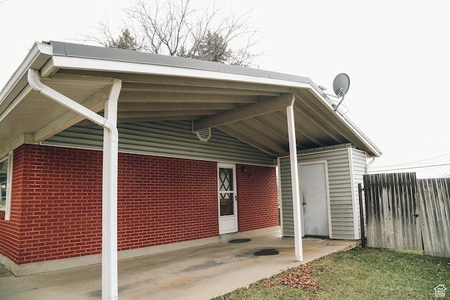 exterior space with a carport, fence, and brick siding