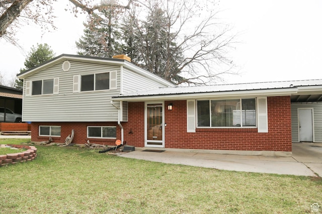 split level home featuring a chimney, brick siding, and a front lawn