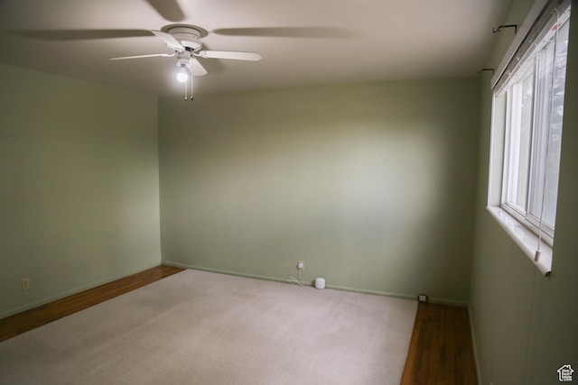 spare room featuring baseboards, wood finished floors, and a ceiling fan