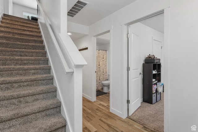 stairs featuring baseboards, visible vents, and wood finished floors
