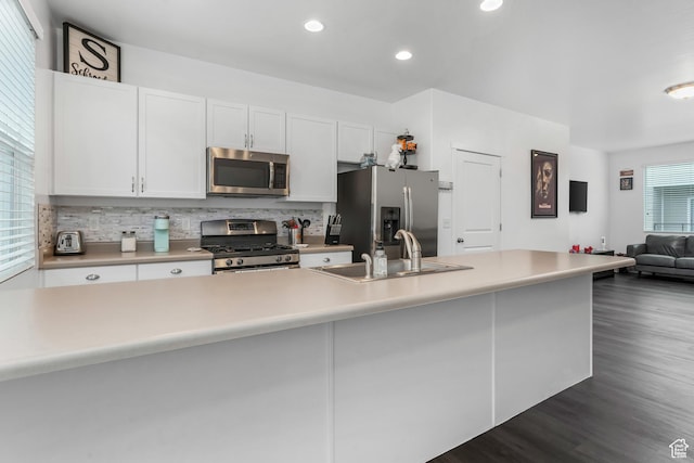 kitchen with light countertops, a sink, tasteful backsplash, stainless steel appliances, and white cabinets