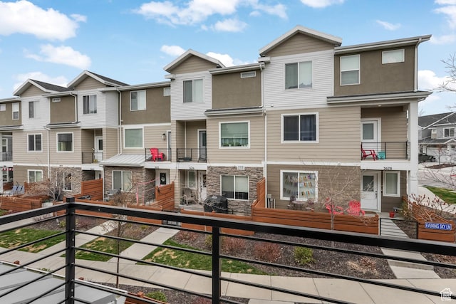 townhome / multi-family property featuring stone siding, fence, and a residential view