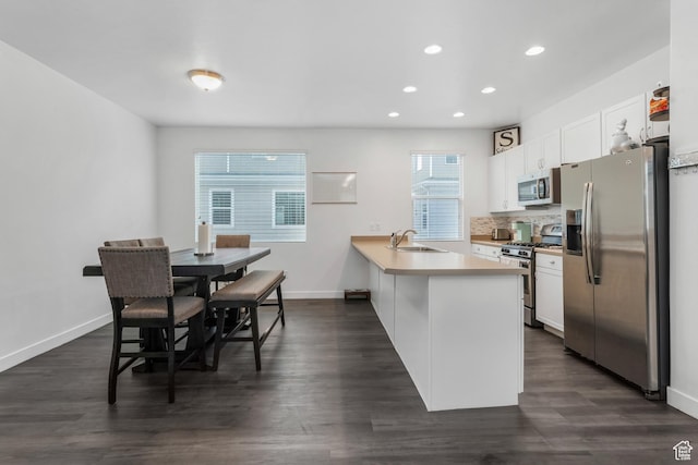 kitchen with white cabinetry, a sink, stainless steel appliances, and a peninsula