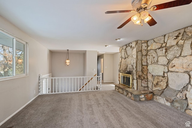 unfurnished living room featuring carpet floors, baseboards, a ceiling fan, and a fireplace