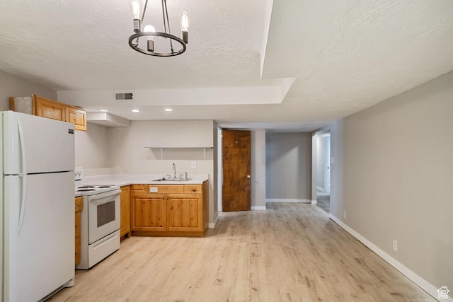 kitchen with light wood-type flooring, white appliances, light countertops, a textured ceiling, and a sink