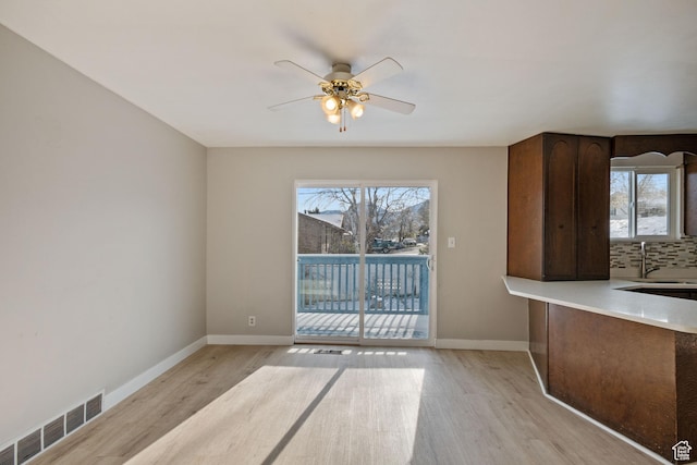 unfurnished dining area with a sink, visible vents, ceiling fan, and light wood-type flooring