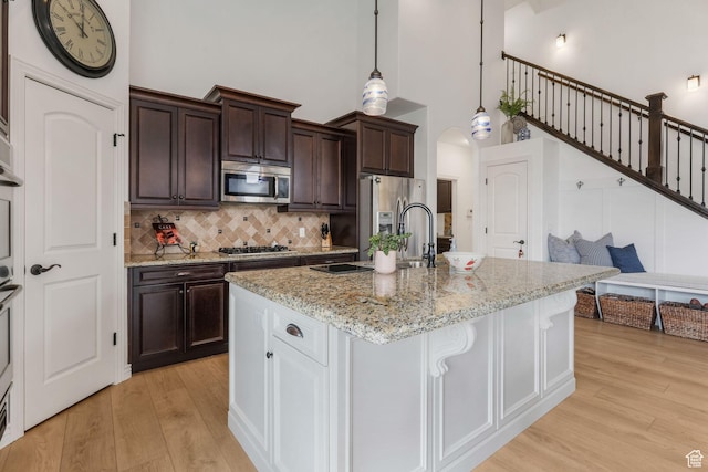 kitchen with arched walkways, light wood-style floors, a sink, and stainless steel appliances