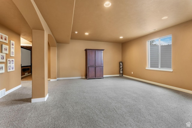 carpeted empty room with arched walkways, baseboards, and recessed lighting