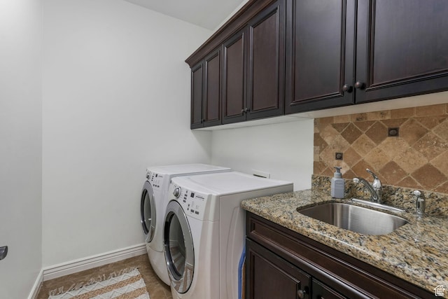 clothes washing area featuring light tile patterned flooring, baseboards, a sink, washer and dryer, and cabinet space