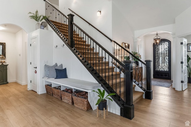 foyer entrance with stairs, wood-type flooring, decorative columns, a towering ceiling, and arched walkways