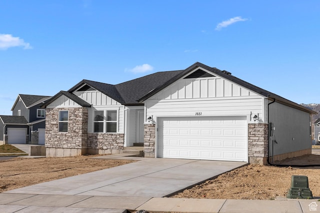 view of front of property featuring a garage, driveway, stone siding, and board and batten siding