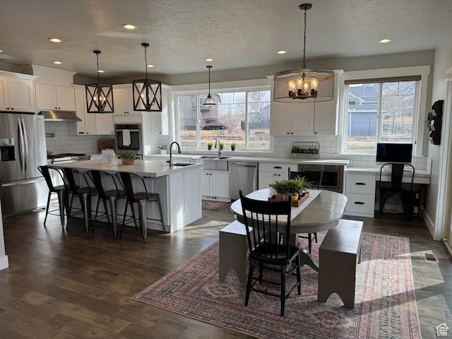 142 S 3500 W, Maeser, UT 84078 - kitchen featuring dark wood-style flooring, stainless steel appliances, white cabinetry, an island with sink, and an inviting chandelier