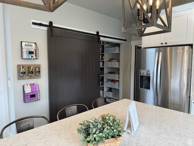 142 S 3500 W, Maeser, UT 84078 - kitchen with white cabinetry, light countertops, stainless steel fridge with ice dispenser, a barn door, and a notable chandelier