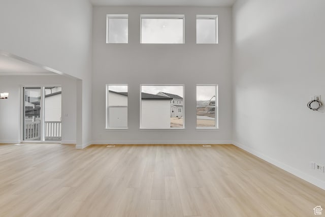6161 W Teton Ranch Dr Unit 342, Herriman, UT 84096 - unfurnished living room featuring plenty of natural light, baseboards, light wood-style floors, and a towering ceiling