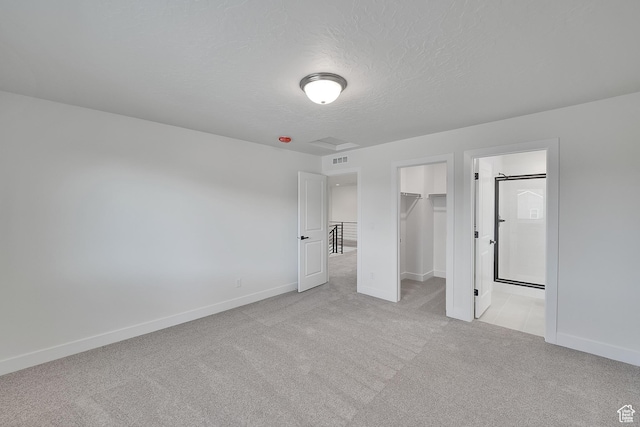 6161 W Teton Ranch Dr Unit 342, Herriman, UT 84096 - unfurnished bedroom featuring light colored carpet, a walk in closet, baseboards, a closet, and a textured ceiling