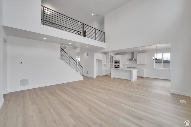 6161 W Teton Ranch Dr Unit 342, Herriman, UT 84096 - unfurnished living room featuring a high ceiling, light wood-style floors, baseboards, stairway, and a chandelier
