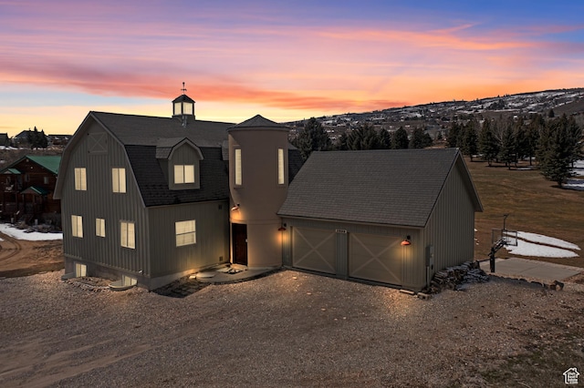 2599 S Foxridge Rd, Garden City, UT 84028 - view of front of house with dirt driveway, a shingled roof, a garage, and a gambrel roof
