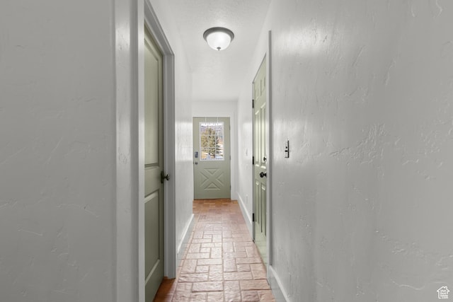 2599 S Foxridge Rd, Garden City, UT 84028 - hall featuring a textured wall, brick floor, baseboards, and a textured ceiling